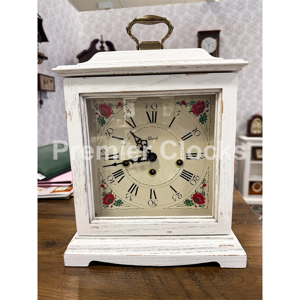 Hermle Austen Mechanical Mantel Clock in White real photo of a distressed white wooden mantel clock with a brass handle and a floral clock face - Premier Clocks
