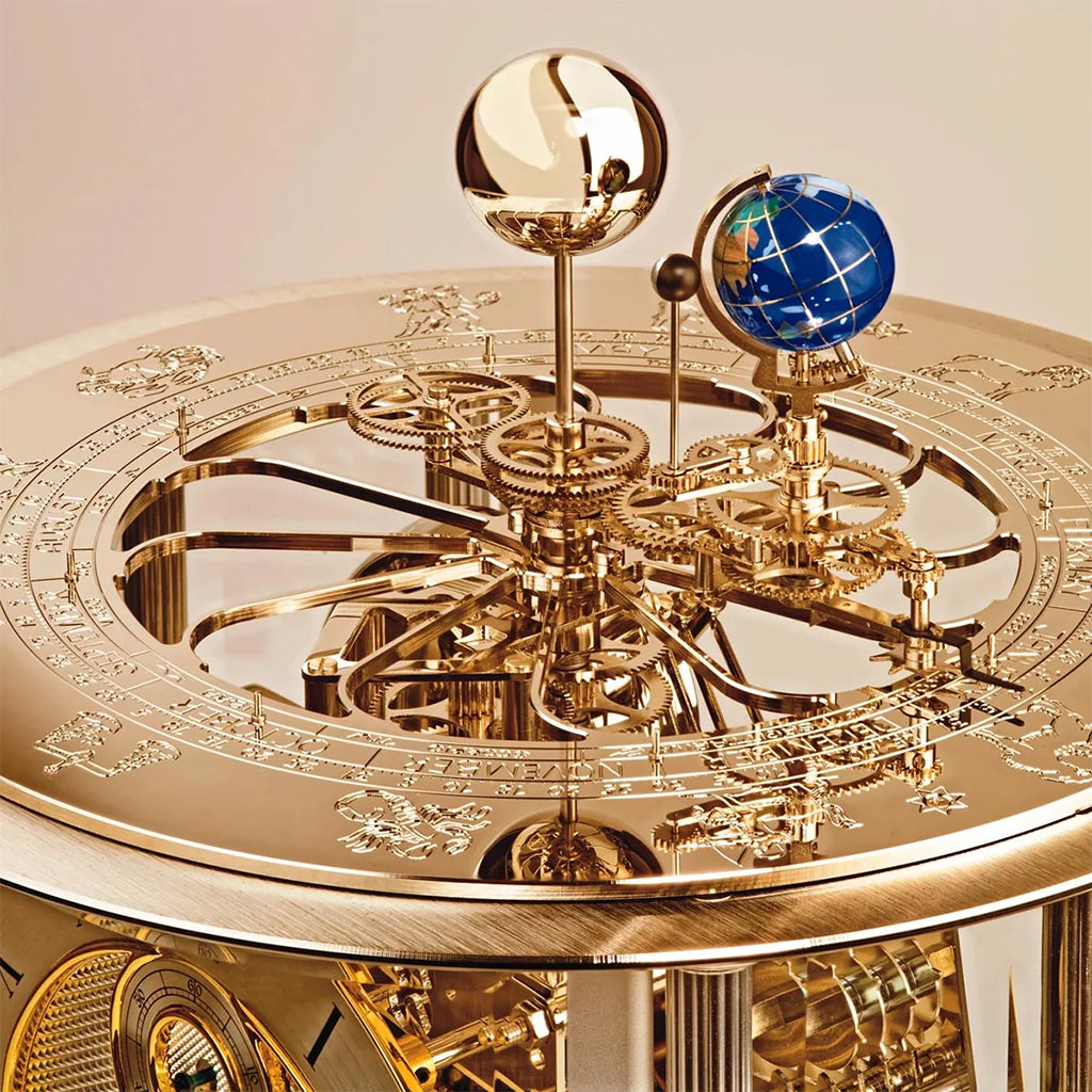 Hermle Tellurium Mantel Clock in Brass - close-up of an ornate brass celestial model or clock mechanism with engraved rings, gears, and two globe-like spheres, one blue and one reflective brass - Premier Clocks