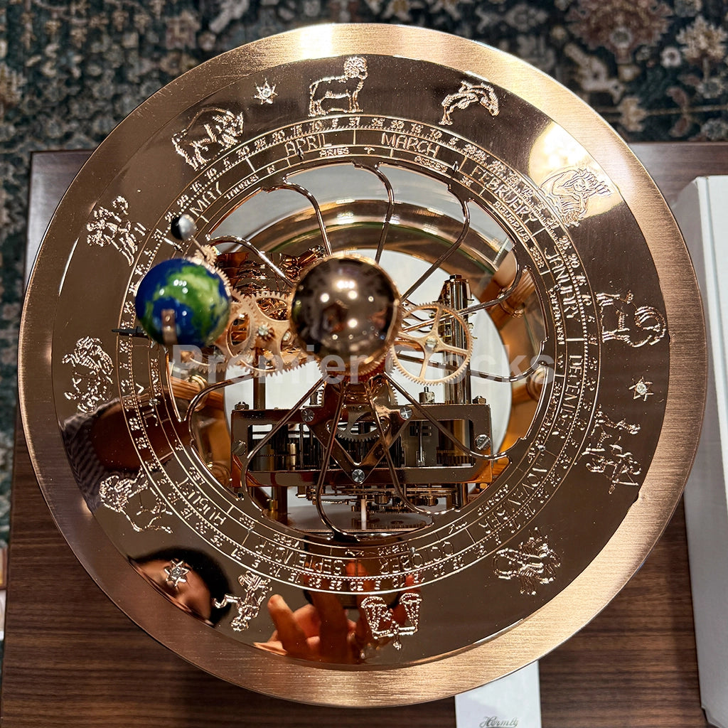 Hermle Tellurium Mantel Clock in White/Rose Gold real photo of a brass celestial globe and zodiac wheel model, featuring engraved zodiac symbols, a central rotating sphere, and colorful decorative accents - Premier Clocks