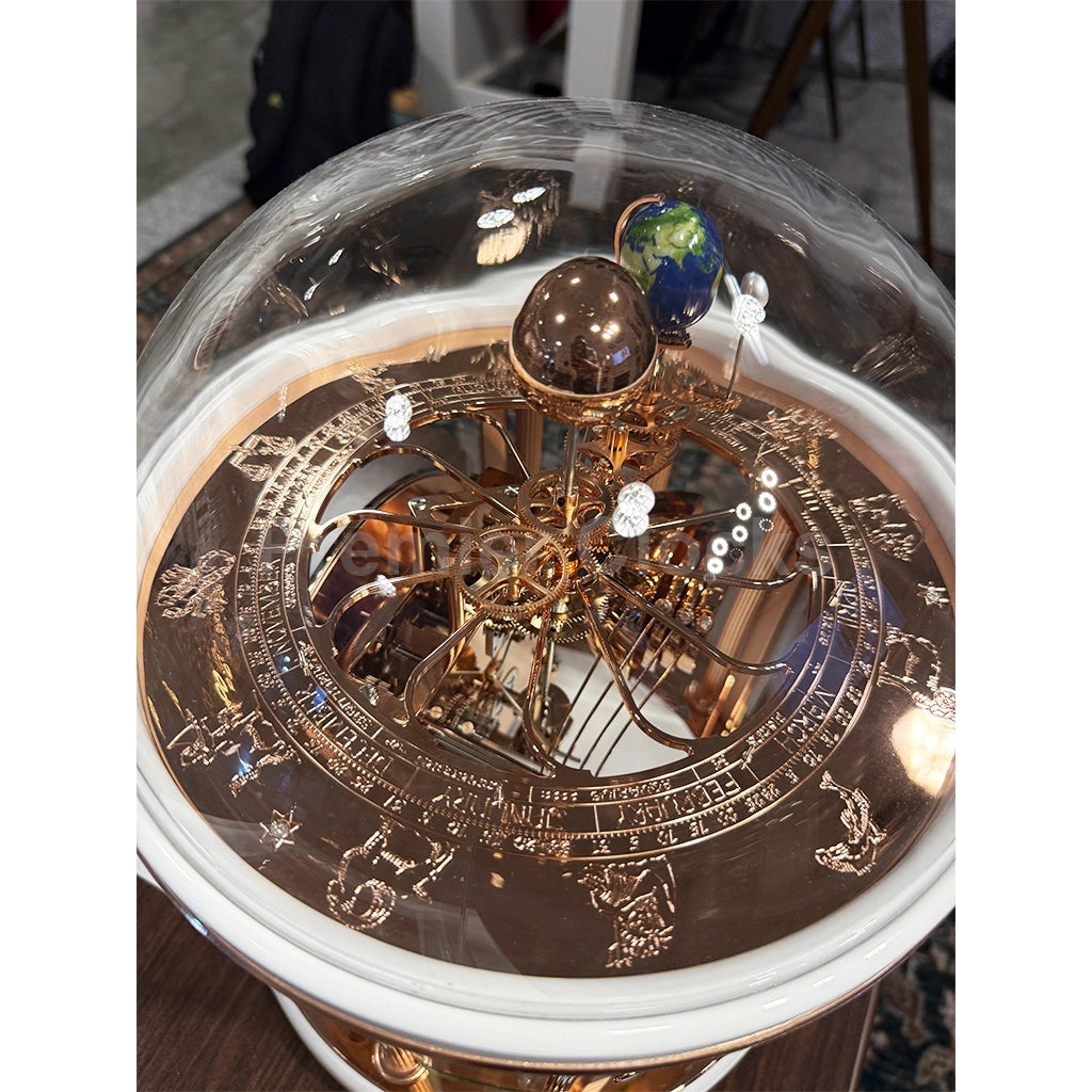Hermle Tellurium Mantel Clock in White/Rose Gold real photo of a decorative golden celestial model under a clear dome, featuring intricate zodiac and planetary details - Premier Clocks