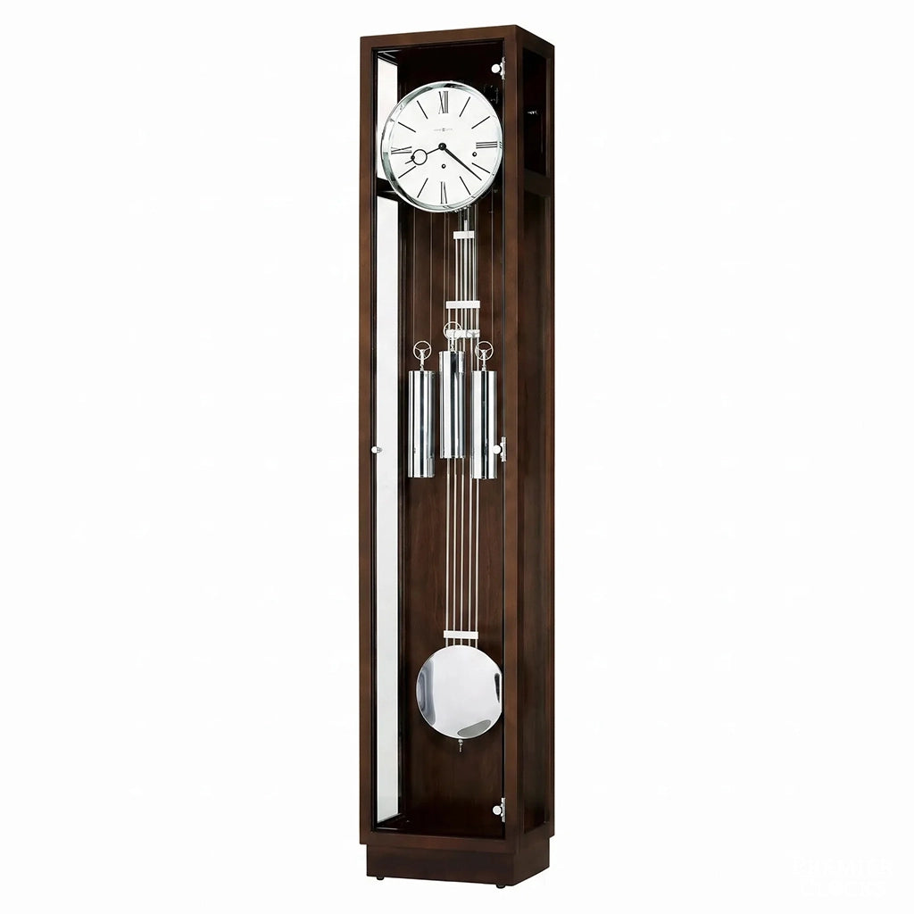 Howard Miller Brenner Floor Clock 660368 is a tall, rectangular wooden grandfather clock with a dark brown finish, featuring a white clock face with black Roman numerals, a silver-toned pendulum, and a polished metal weight at the bottom - Premier Clocks